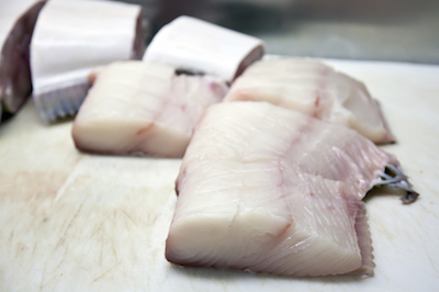 Pieces of halibut fish wait to be cut into filets.
