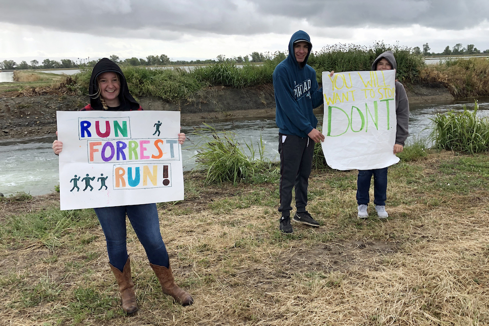 people holding signs of support for runners