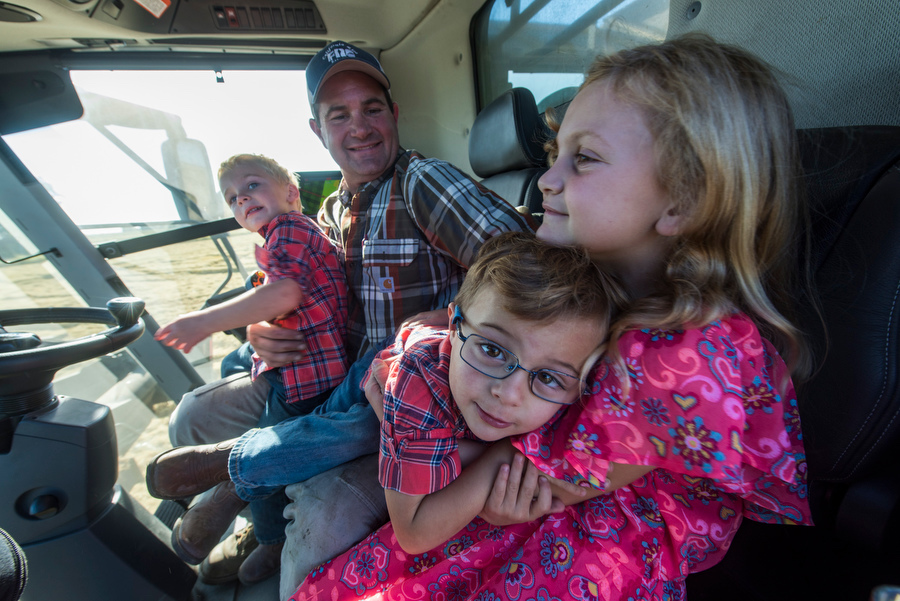 rice farmer driving rice harvester with 3 kids