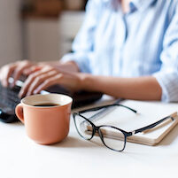 woman workplace in kitchen with laptop, cup of coffee, spectacles.