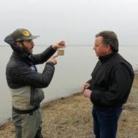 radio host Joe Getty interviewing farmer in flooded field